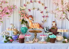 the dessert table is decorated with pink flowers and deer figurines