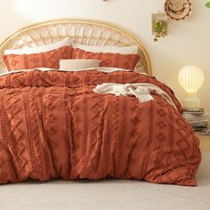 a bed with an orange comforter and pillows