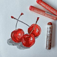 some crayons are laying next to two cherries