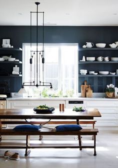 a dining room table with two benches and some plates on the wall behind it in front of a window