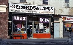 an empty street in front of a record store with signs on the doors and windows