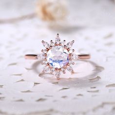 an engagement ring with a large white diamond surrounded by smaller round cut diamonds on top