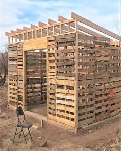 a wooden structure sitting in the middle of a field with a chair next to it