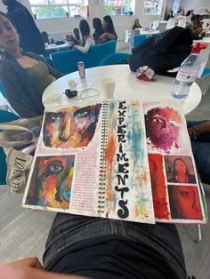 a person sitting at a table with some art work on it