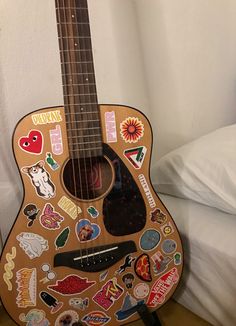 a guitar covered in stickers sitting on top of a bed