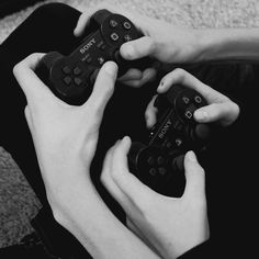 two people are holding video game controllers in their hands while sitting on the floor together