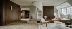 a living room filled with lots of furniture and tall wooden walls next to a stair case