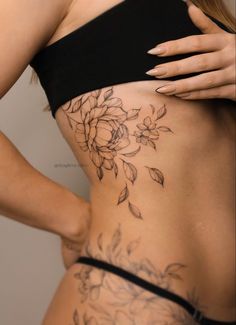 a woman's back with flowers on it and her lower half covered in tattoos