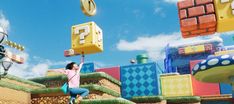 a woman is jumping in front of an array of nintendo themed buildings and games on display