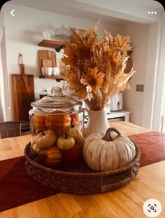 a glass jar filled with pumpkins and gourds on top of a wooden table