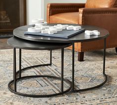 two coffee tables sitting on top of a rug in front of a brown leather chair