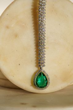 Enhance your elegance with the Safi Diamanté Accent Maang Tikka, a radiant piece crafted in a rhodium-plated silver finish. Available in stunning emerald green or sapphire blue, this exquisite maang tikka features a paved setting with glistening white diamante AD stones complemented by teardrop-shaped stones in your chosen hue. Its smaller size ensures a flattering fit for all face sizes, designed perfectly to complement our Sharmine necklace set. Key Features: Elegant Design: Paved setting with Emerald Maang Tikka, Maang Tikka Design, Tikka Designs, Mang Tikka, Custom Outfits, Artificial Jewelry, Bridal Jewelry Vintage, Indian Bridal Jewelry Sets, Ear Chain