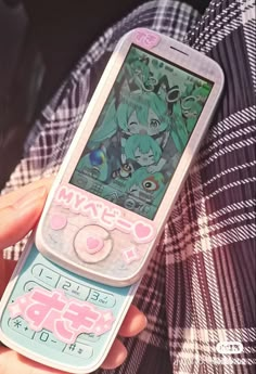 a person holding an old cell phone in their hand with anime stickers on it