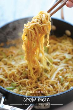 chopsticks holding up noodles in a wok