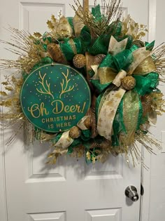 a christmas wreath with green and gold decorations hanging on the front door for someone's house