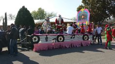 some people are standing in the street and one is riding on top of a float