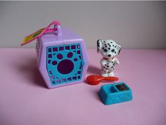 a toy dog and its kennel on a pink surface