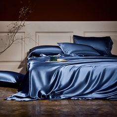 a bed with blue sheets and pillows on top of it in front of a wall