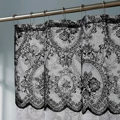 black and white lace curtains hanging from a metal rod in front of a window with blue walls