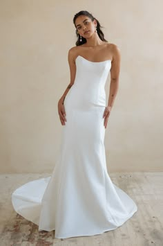 a woman in a white wedding dress posing for the camera with her hands on her hips