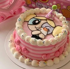 a pink and white cake with a cartoon dog on it's side, next to a hello kitty box