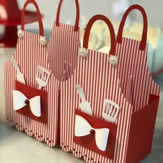 three red and white paper bags sitting on top of a table next to each other