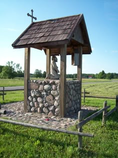 a small wooden structure with rocks and a cross on top