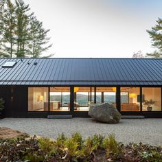 a large rock sitting on top of a gravel field next to a building with glass windows