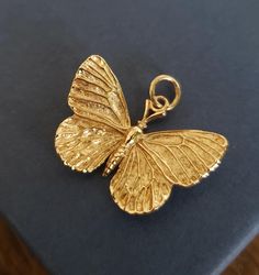 a gold butterfly charm sitting on top of a book