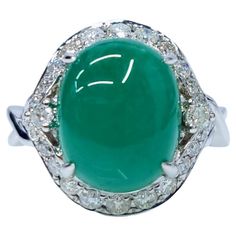 This exquisite ring features a captivating oval-shaped cabochon Colombian emerald, weighing 4.85 carats. The emerald's rich green color, characteristic of Colombian emeralds, is complemented by a sparkling halo of diamonds, totaling 0.44 carats. The ring is crafted in 18k white gold, providing a luxurious and timeless setting for these precious gemstones. The ring showcases a unique and elegant design that highlights the beauty of the Colombian emerald. The oval cabochon cut of the emerald creates a smooth, rounded surface that reflects light beautifully. The diamond halo adds a touch of sparkle and brilliance, enhancing the emerald's color and overall appeal. The 18k white gold setting provides a luxurious and timeless backdrop for the gemstones, complementing their natural beauty. Except Luxury Oval Cabochon Diamond Gemstones, Luxury Oval Emerald Gemstones, Exquisite Oval Platinum Gemstones, Luxury Emerald Ring With Oval Cabochon, Luxury Oval Platinum Gemstones, Luxury Multi-stone Oval Cabochons, Oval Multi-stone Emerald Gemstones, Elegant Cabochon Emerald Ring For Formal Occasions, Formal Multi-stone Oval Cabochon Gemstones