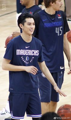 two young men standing next to each other on a basketball court