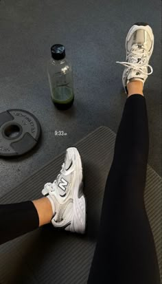 a person is sitting on a mat with their feet propped up next to a bottle of water