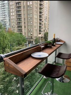 a wooden table sitting on top of a balcony next to a tall building with lots of windows