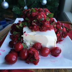 a piece of cake with cherries on it sitting on a plate next to some grapes