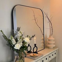 a vase with flowers on a table next to a mirror