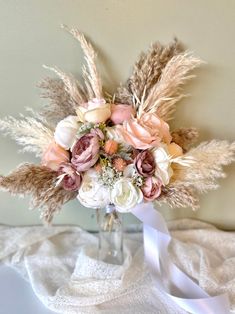 a vase filled with lots of flowers on top of a white cloth covered tablecloth