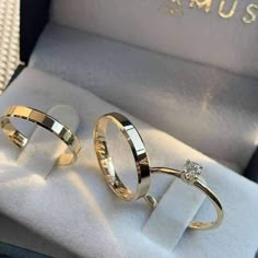 two gold wedding rings sitting in a box