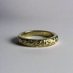 a gold wedding band with flowers on it