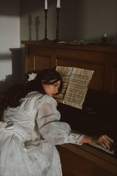 a woman in white dress sitting at a piano