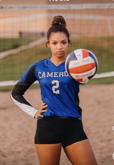 a young woman holding a volleyball in front of a net