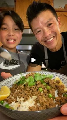 a man and boy are smiling while holding a plate of food in front of them