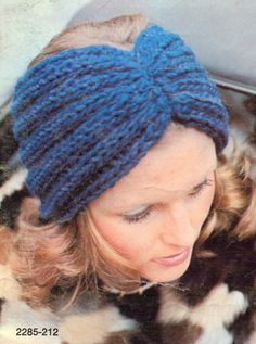 a woman wearing a blue knitted headband and looking down at her cell phone