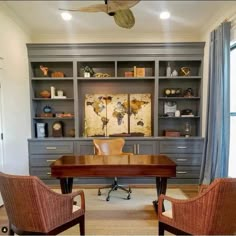 two chairs are in front of a desk with a large bookcase behind it and a ceiling fan