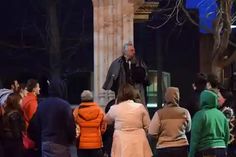 a group of people standing around each other in front of a building at night time