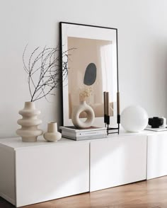 a white shelf with vases and other items on top of it in a room