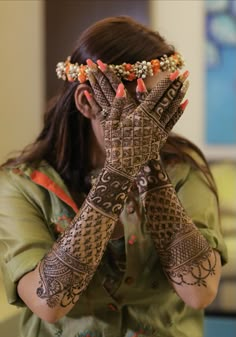 a woman holding her hands up to her face with henna tattoos on it's arms