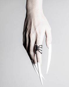 a person's hand holding two white knives with black bows on the tip of their fingers