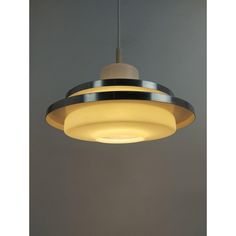 a yellow light hanging from the ceiling in a room with grey walls and flooring