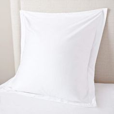 a bed with white sheets and pillows on it