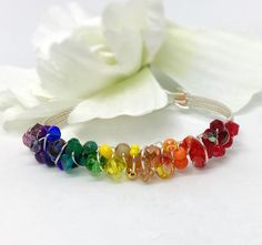 LGBTQIA+ Pride Bracelet, Beaded Bracelet, Gay Pride Bracelet, Silver Bracelet,  Wire-Wrapped Bracelet, Rainbow Bracelet  Beautiful, colorful, eclectic, beaded, wire-wrapped bracelet.   Various sizes and shapes of beads wrapped around either a  silver plated wire-wrapped bracelet. Wire is high quality non tarnish silver plated wire. Red, orange, yellow, green, blue, indigo and violet. The perfect colors of the rainbow -ROYGBIV!   Dress it up or down, mix it up with others or wear it alone.  This is the perfect bracelet for any outfit.   These are custom made at the time of purchase. Specify the length needed when you place your order.  Each one of these bracelets is individually made by me. The beads in each will be slightly different than what is pictured but equally as beautiful. Gay Pride Bracelet, Colorful Eclectic, Pride Bracelet, Bracelet Rainbow, Lgbtqia Pride, Tarnished Silver, Wire Wrapped Bracelet, Rainbow Bracelet, Colors Of The Rainbow